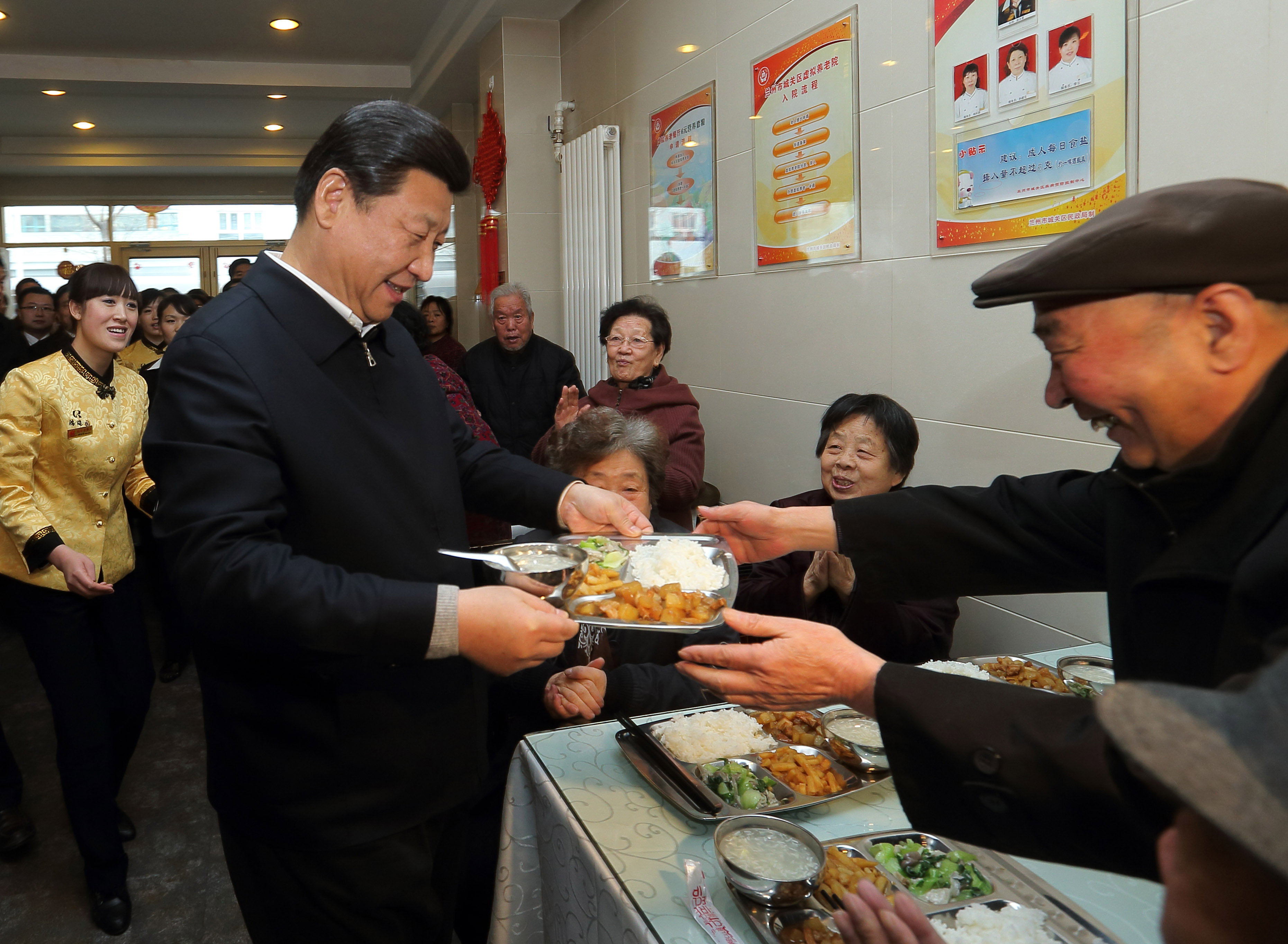 2013年2月4日，习近平总书记在兰州一家“虚拟养老院”的养老餐厅为七旬老人端饭。