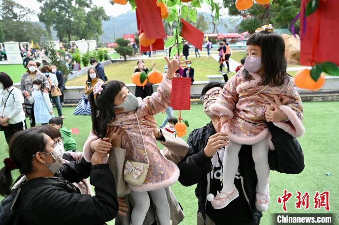 家长抱起女童在许愿树上挂上“宝碟”许愿。　李志华 摄