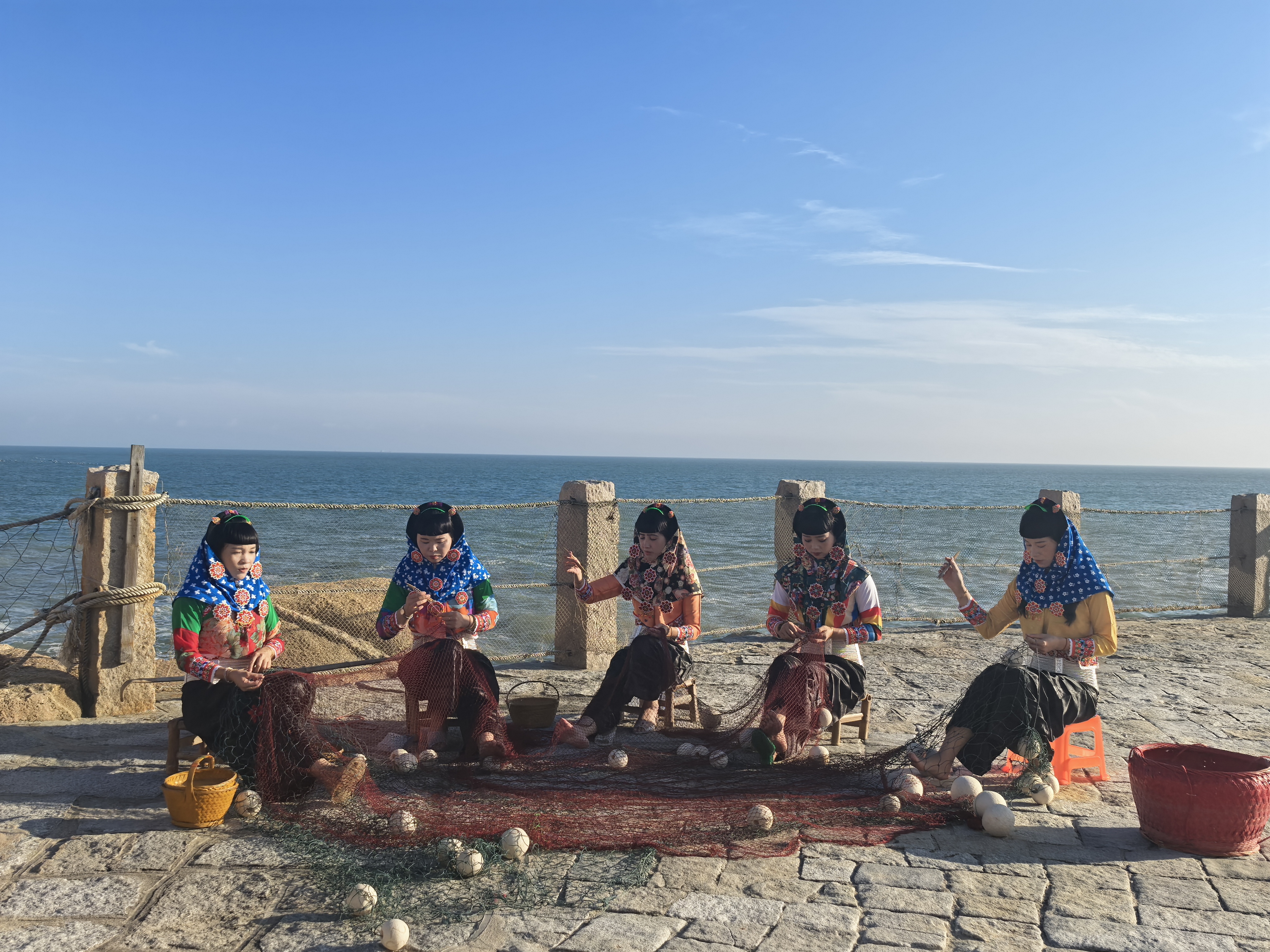 身着传统服饰的惠安女在海边补渔网。刘晓宇 摄