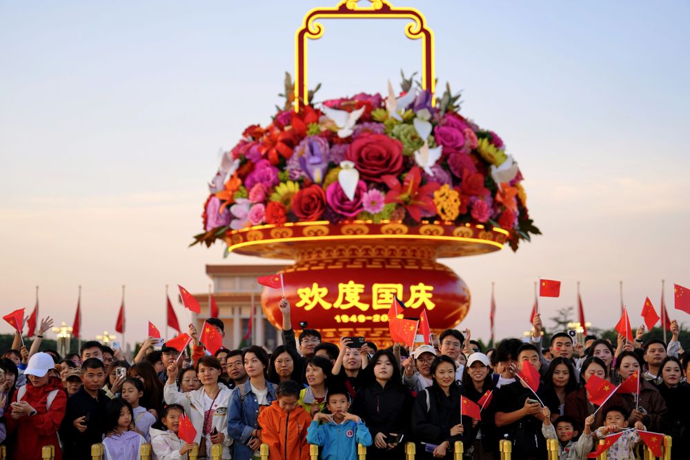 人民领袖|播下爱我中华的种子 2025年10月1日,在北京天安门广场,人们观看升国旗仪式后挥舞国旗。